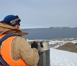 Paul taping a cover on an exhaust vent with ice bergs in the distance.