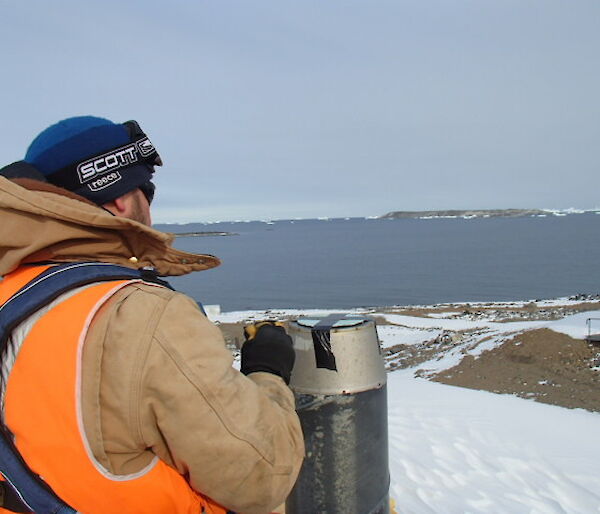 Paul taping a cover on an exhaust vent with ice bergs in the distance.