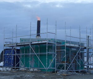 Photo of the incinerator building from outside with flames coming out of the incinerator flu during the last burn before its removal