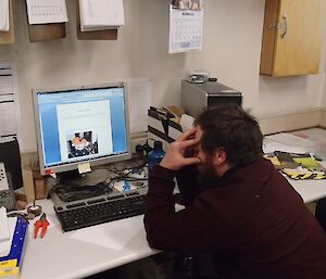 Aaron sitting in front of his computer head in hands looking stressed