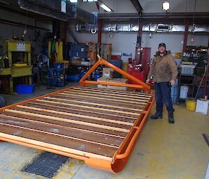 Diesel mechanic standing next to the Smith sled which has a fresh coat of paint and new deck boards fitted