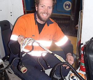 Diesel mechanic sitting in a Hägglunds vehicle with the wiring loom in his hands