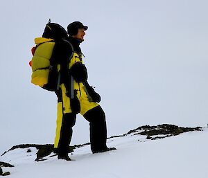 Nick standing in the snow dressed in his outdoor walking gear and pack on