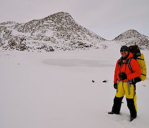 Rich on the shore of Scale Lake which is frozen and covered with snow with rocky hills in the back ground