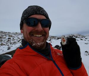 Rich in the field smiling while holding up a piece of sushi made by the chef on station the day before