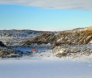 Watts hut nestled in the Vestfold Hills which are covered in snow on a bright sunny morning