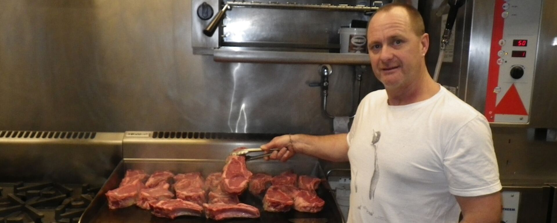 Rodney the chef standing in front of the hot plate cooking the steak for dinner