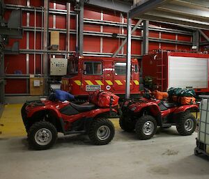 The Hägglunds fire vehicle with the two SAR quads in the foreground parked in the emergency vehicle shelter