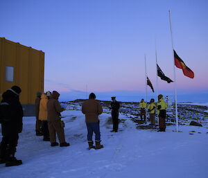 Standing in front of the Australian, Aboriginal and New Zealand flags, Gavin conducts the Dawn Service while the rest of the Davis crew look on.