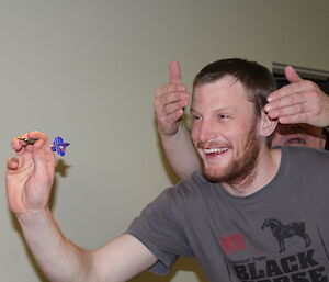 Gavin holding his hands over Nick’s eyes as he takes aim at the dart board