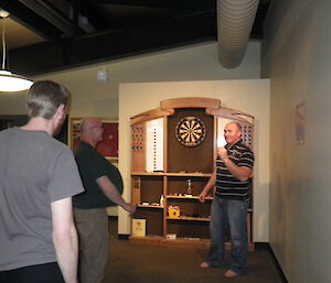 Tim and Gavin and Nick in front of dart board while others watch