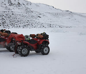 Quads in the foreground with expeditioners in the distance on the sea ice