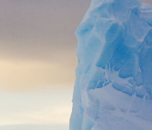 An iceberg gives of a blue hue under the light of a cloudy dawn sky