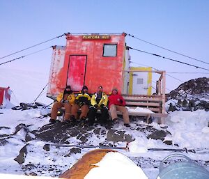 Gavin, Jeff, Mark and Keith sit on a bench seat at Platcha hut