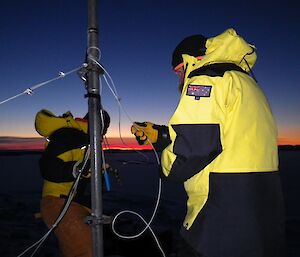 Undertaking repairs to an antennae cable against a twilight sky