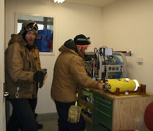 Two expeditioners standing at work bench refilling BA cylinder