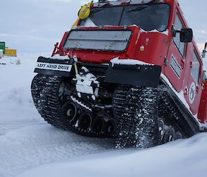 Red Hägglunds emerging from a steep inclines of snow