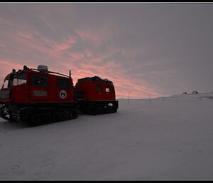 Red Hägglunds on the sea ice beneath a sunset sky