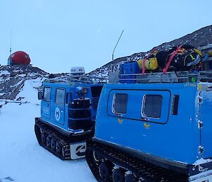 Hagglund vehicle parked on the edge of the frozen lake with the hut in the background