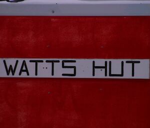 Watts hut sign mounted on the external wall of the hut