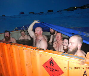 Mid-winter swimmers all huddle in the temporary warm bath to watch and support the other swimmers going in