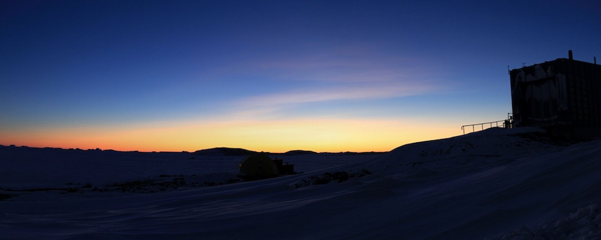 The meteorology hut sits on the right with a blue and gold twilight sky behind.