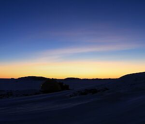 The meteorology hut sits on the right with a blue and gold twilight sky behind.