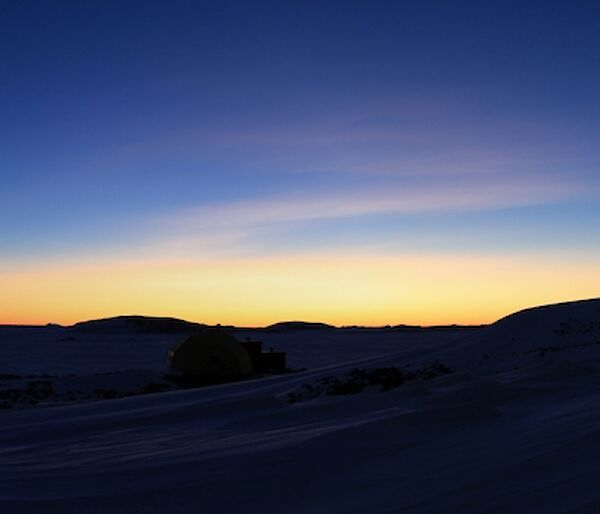 The meteorology hut sits on the right with a blue and gold twilight sky behind.