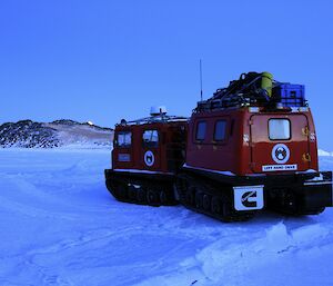 Red Hägglunds parked on the sea ice with Turner Island in the foreground