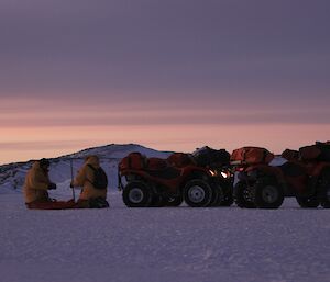 Dr Bob and Gavin drilling thorugh the sea-ice. The quad bikaes are parked next to them.