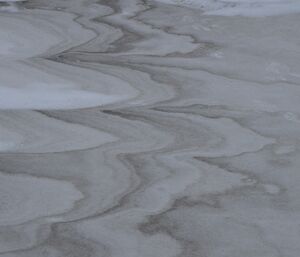 Wind blown dirt making patterns in the packed snow