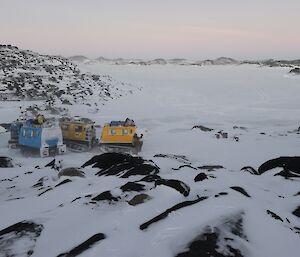 The blue and yellow Hägglunds parked close to each other with the frozen fjord in the background