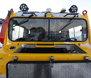 A close up of two expeditioners in the front seats of the yellow Hagglund as they cross the land bridge at Pioneer Crossing