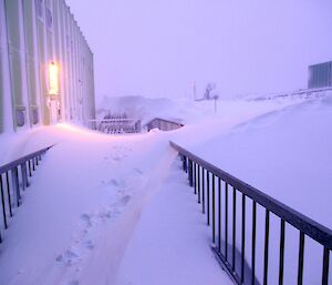 A large mound of blown snow from the blizzard that is covering the back door to the Sleeping Medical Quarters