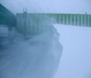 The wind lifting snow of a large Blizz tail at the back of the Sleeping and Medical Quarters