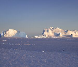 The sun brings out the beauty of the ice bergs stuck fast for the winter in the frozen sea ice