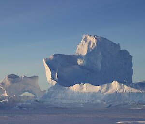 The sun brings out the beauty of the ice bergs stuck fast for the winter in the frozen sea ice