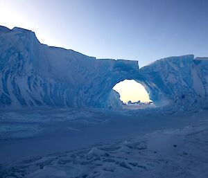 A large ice berg stuck in the fast ice with a large weathered hole on the righthand side