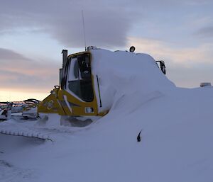 The snow groomer buried in snow after the blizzard