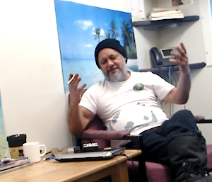 Expeditioner throwing his hands up in disbelief that the SAR alarm is going off and he has to leave his comfy chair
