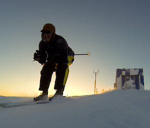 Expeditioner skiing in a tuck position, coming down the hill with the Met Building in the background