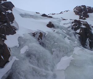 The water which would normally be cascading over the rocks has frozen in time with a layer of ice covering the rocks