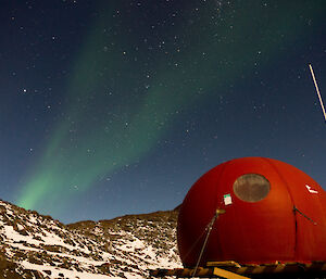 The melon at night with a green Aurora drifting over head in the clear night sky