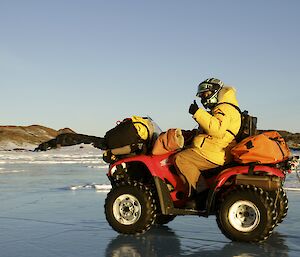 Bob with his quad kitted up giving thumbs up as he drives by on the sea ice