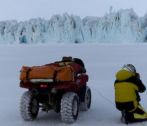 Rich kneeling by his quad taking pictures of the Sorsdal Glacier