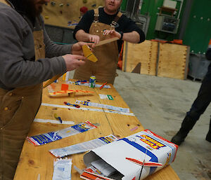 Aaron and Tim standing at table constructing balsa aircraft