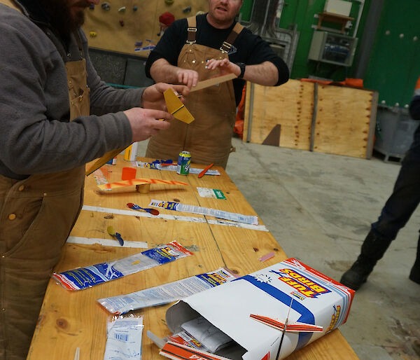 Aaron and Tim standing at table constructing balsa aircraft