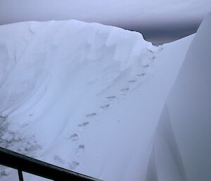 Foot prints going up and over the massive pile of snow in front of the living quarters