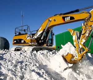 The station excavator being used to clear away the snow from the building