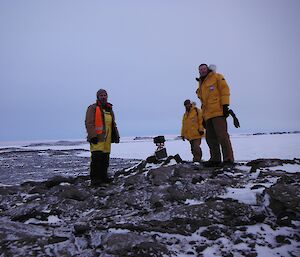 Three expeditioner standing on location of a permanent infield camera